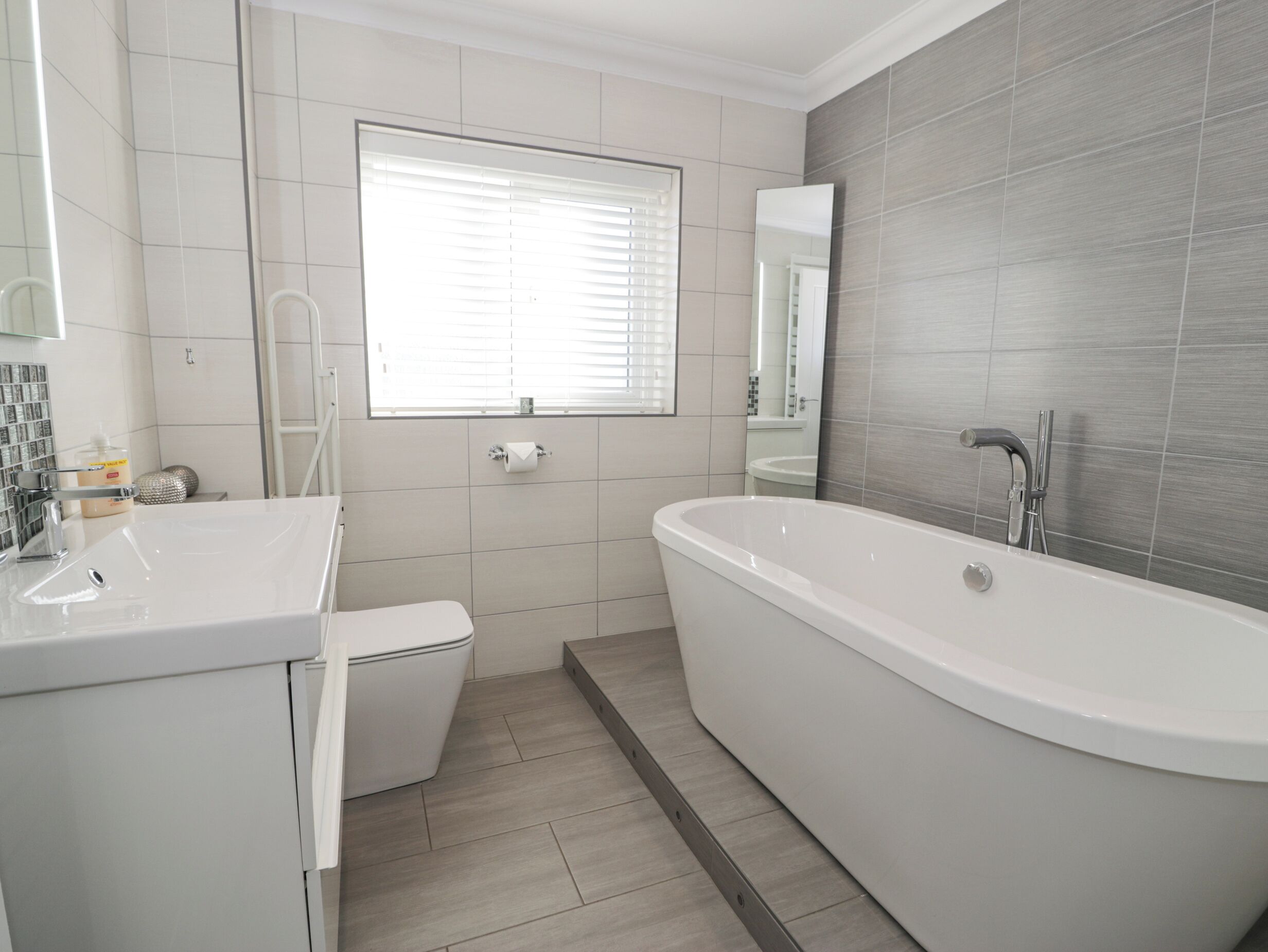 Een moderne badkamer met een vrijstaand bad, een toilet en een wastafel.