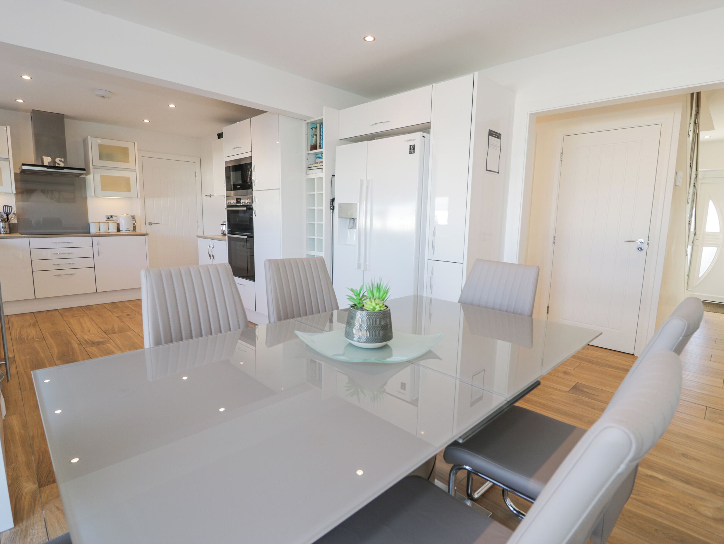 A modern kitchen with white cabinets, a built-in oven, and a stainless steel range hood.