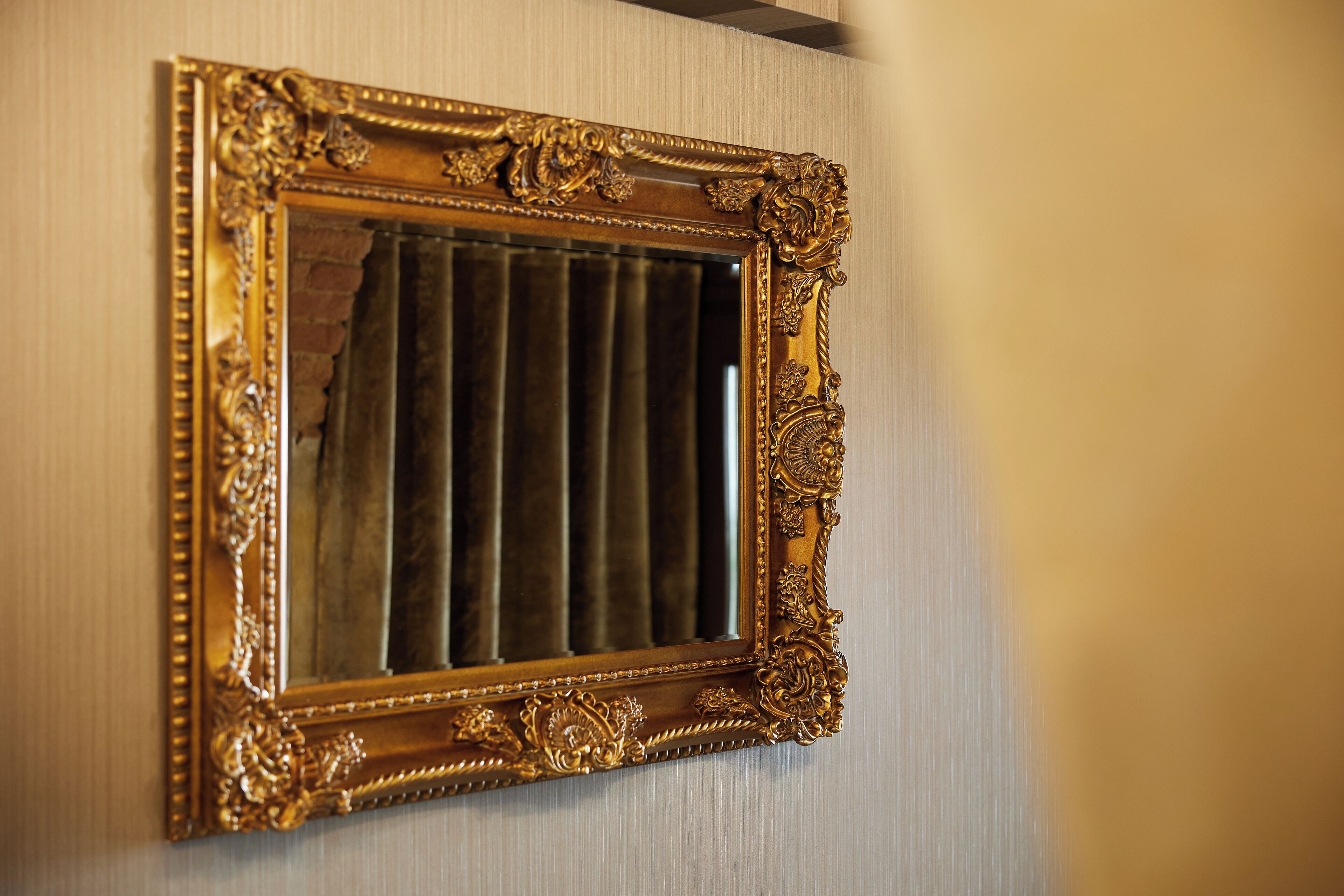 A wall-mounted mirror with an ornate gold frame.