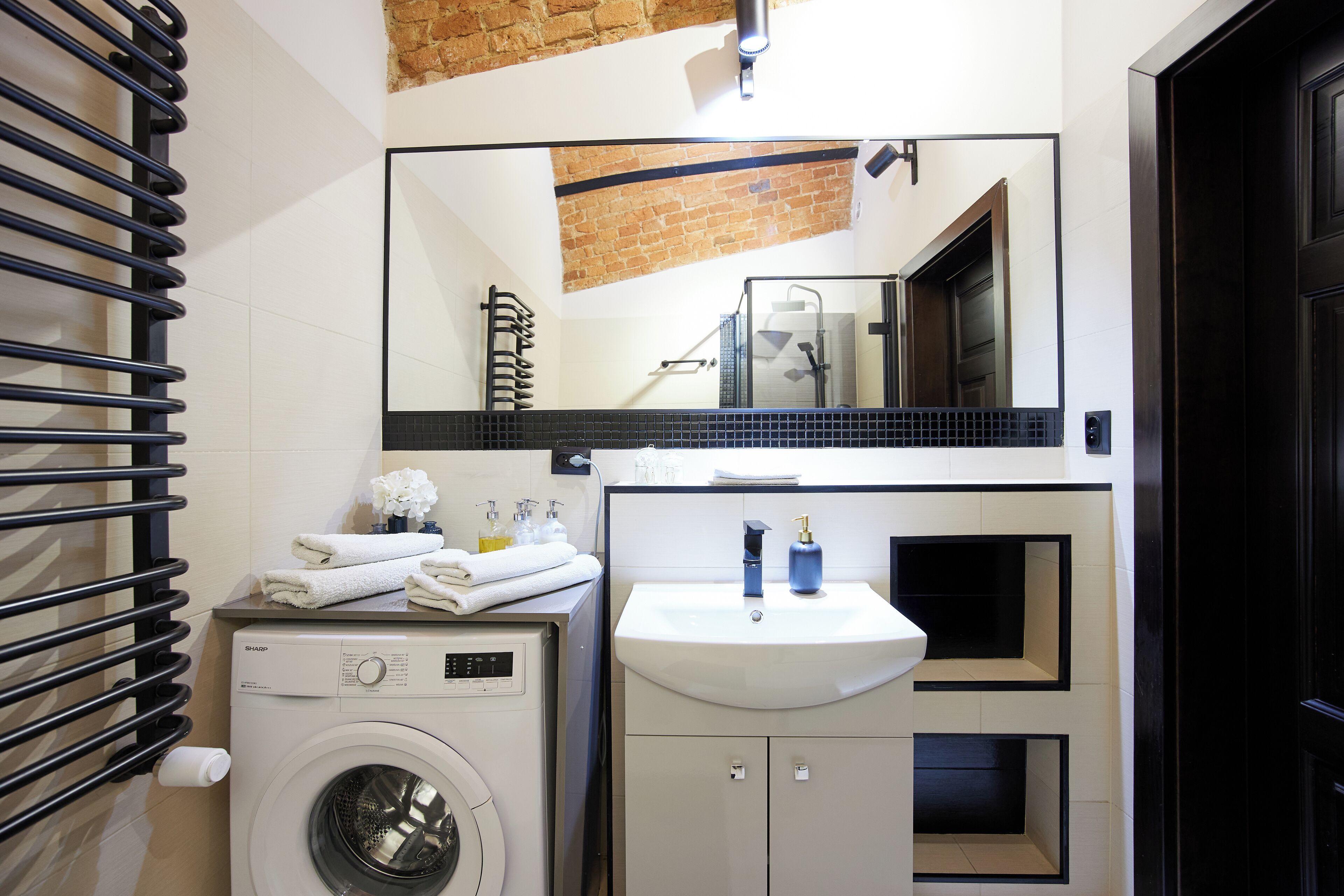 A modern bathroom with a washing machine, a sink, and a mirror.