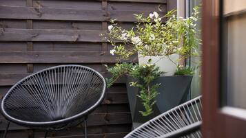 A wooden wall with two black wire chairs and a potted plant with white flowers.