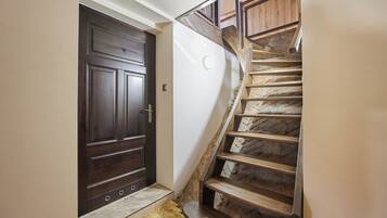 Una puerta de madera oscura, una escalera de piedra con escalones de madera y una pared blanca.