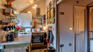 A compact kitchen with a wooden countertop, a kettle, and various utensils. There is a small oven and a sink. - Penn an Vownder (The Lizard)