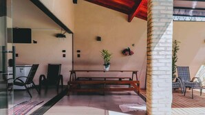 A modern interior with a wooden bench, chairs, a potted plant, and a brick column.