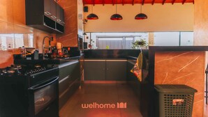 A modern kitchen with a stove, oven, and cabinets, a small island, pendant lights, and a trash bin.