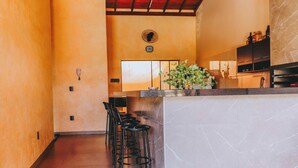A modern kitchen with a bar area, a clock on the wall, and a potted plant.