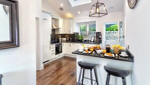 A modern kitchen with white cabinetry, a black countertop, and a skylight. - River Barn (Grange-over-Sands)