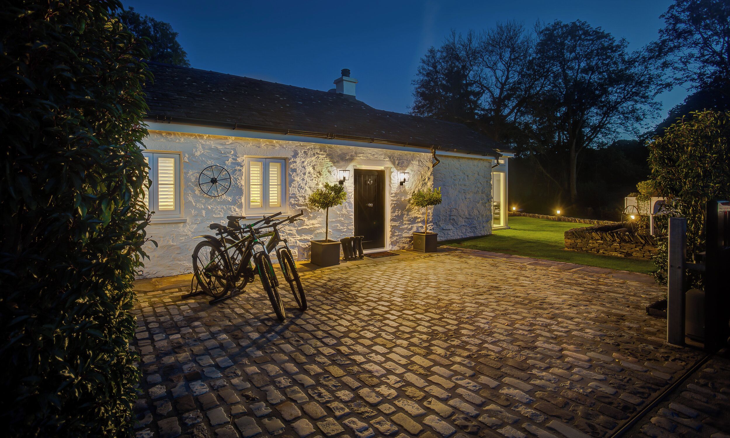 Un edificio de piedra con un camino de adoquines, una bicicleta y una entrada bien iluminada.