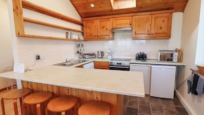 Una cocina con armarios de madera, una isla grande con taburetes, lavavajillas, estufa y tostadora.
