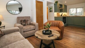 A modern living room with two sofas, a coffee table, and a round mirror on the wall. - Esk Pike (Windermere)
