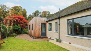 A modern house with a wooden extension, a paved driveway, and a well-maintained lawn. - Esk Brae (Langholm)