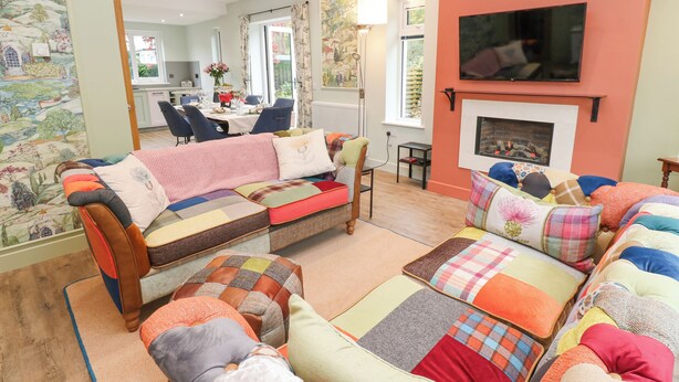 A cozy living room with a sofa set, a fireplace, and a television mounted on the wall. - Esk Brae (Langholm)