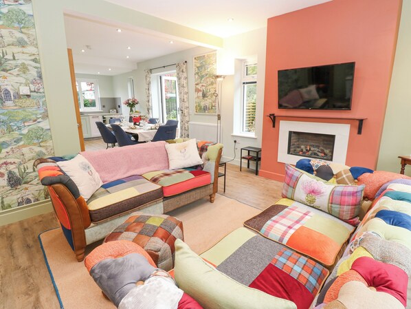 A cozy living room with a sofa set, a fireplace, and a television mounted on the wall. - Esk Brae (Langholm)
