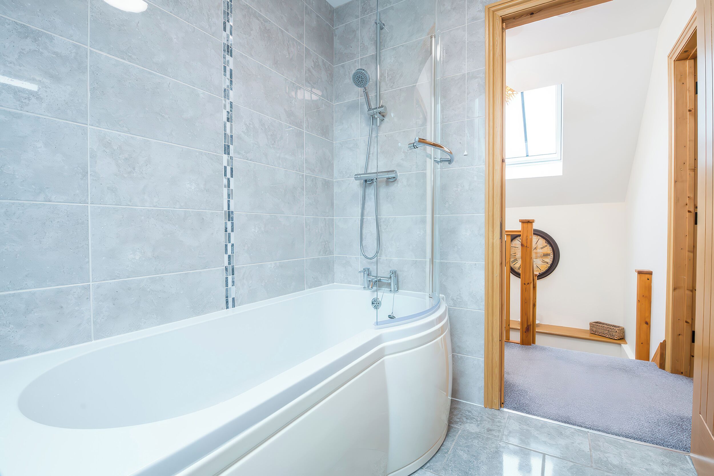 A modern bathroom with a freestanding bathtub, a shower area, and a wooden bench.