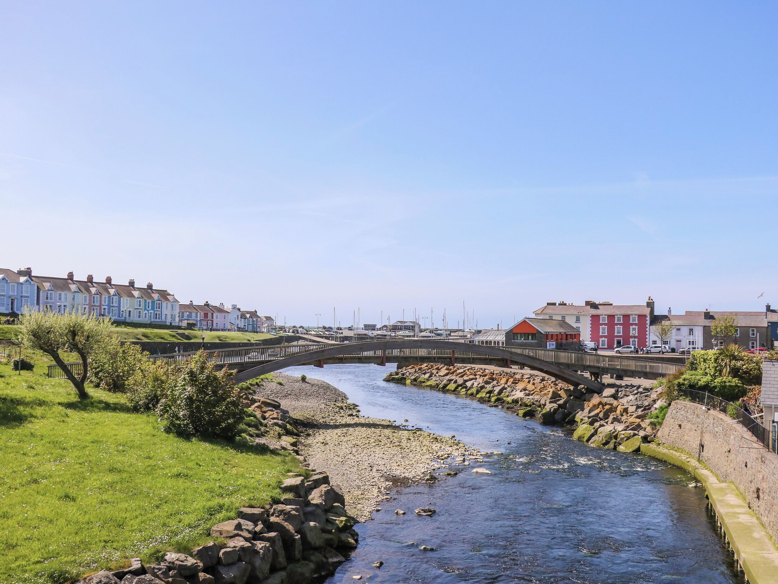 A river flowing through a town with a stone bridge, houses, and a marina.