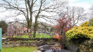 Een terras met een ronde tafel en stoelen, omringd door stenen muren en verschillende planten.