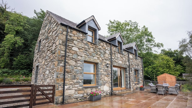A stone house with a patio, a wooden gate, and a small shed. - Carreg Wen (Harlech)