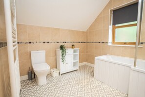 Ein Badezimmer mit Toilette, Waschbecken, Badewanne und einem Fenster.