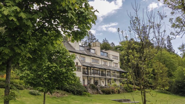 A large, multi-story building with a prominent balcony area, surrounded by a well-maintained lawn and trees. - Deer Wood At Applethwaite Hall (Windermere)