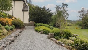 A gravel path leading to a house with a white exterior and a chimney, surrounded by lush greenery and a clear sky. - Deer Wood At Applethwaite Hall (Windermere)