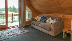 A cozy room with a wooden ceiling, a sofa with patterned cushions, a small table, and a fluffy rug. - Holly (Winkleigh)