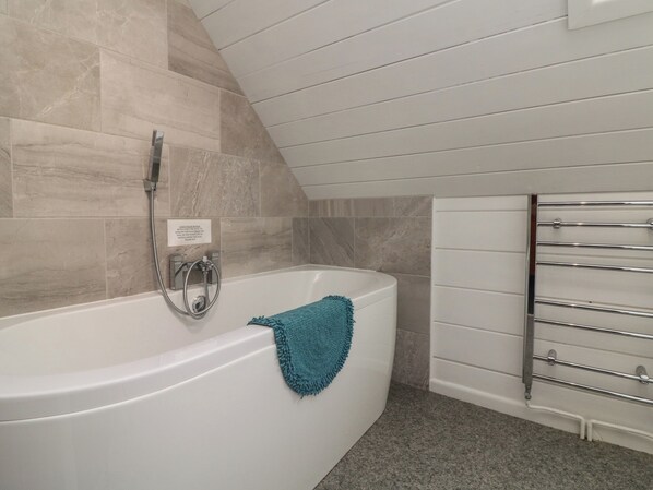 Une salle de bain moderne avec une baignoire sur pieds, une pomme de douche et un porte-serviettes.