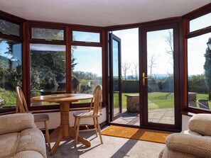 Ein Eckzimmer mit Esstisch und Stühlen, große Glastüren zu einem Garten.