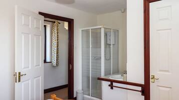 A hotel room with a bed, a bathroom with a glass shower enclosure, and a white sink.