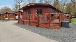 A wooden cabin with a porch and a gravel driveway. - Brightwater Lodge (Windermere)