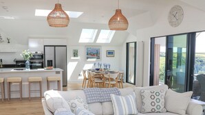 A modern living room with a sofa, a dining area, and a kitchen. - Sea Kist (Salcombe)