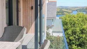 A balcony with wicker furniture and a view of a lake and hills. - Sea Kist (Salcombe)