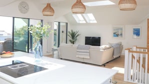 A modern living room with a sofa, a TV, and a dining area with a table and chairs. - Sea Kist (Salcombe)