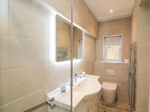 Un baño moderno con cabina de ducha de vidrio, un lavamanos blanco y un inodoro.