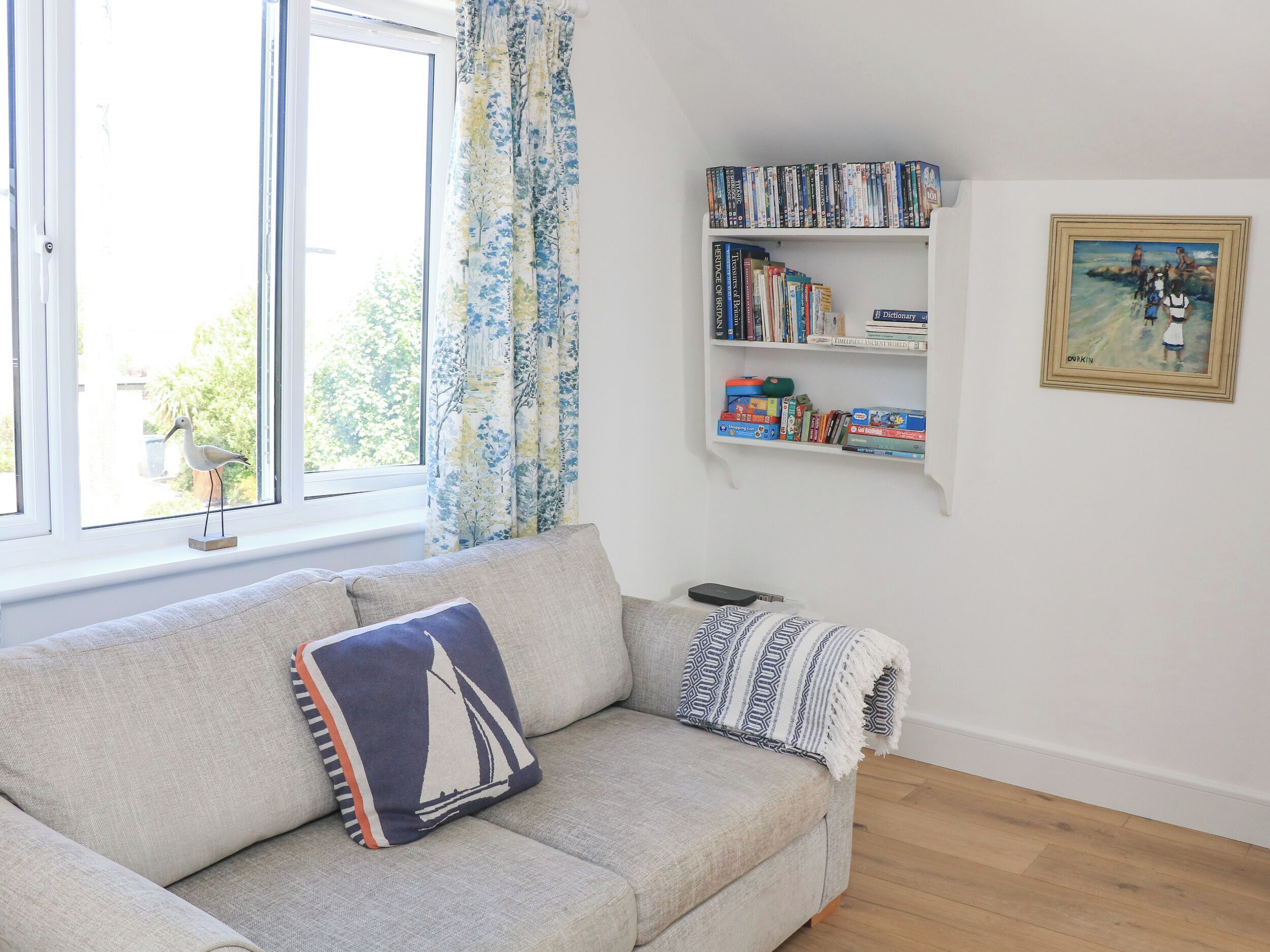 A living room with a sofa, a bookshelf, and a painting on the wall.