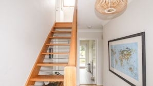 A wooden staircase with a woven light fixture above, leading to a room with a world map on the wall. - The Palms (Pwllheli)
