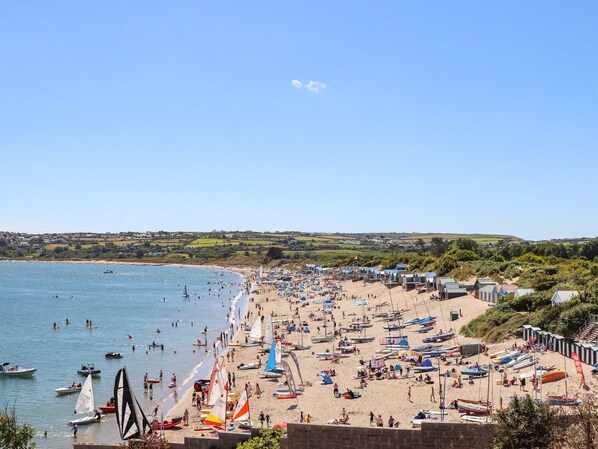 A beach with numerous boats and people.