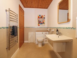 A bathroom with a wooden ceiling, a towel rack, a toilet, a sink, and a poster on the wall. - Ringstead Lodge (King's Lynn)