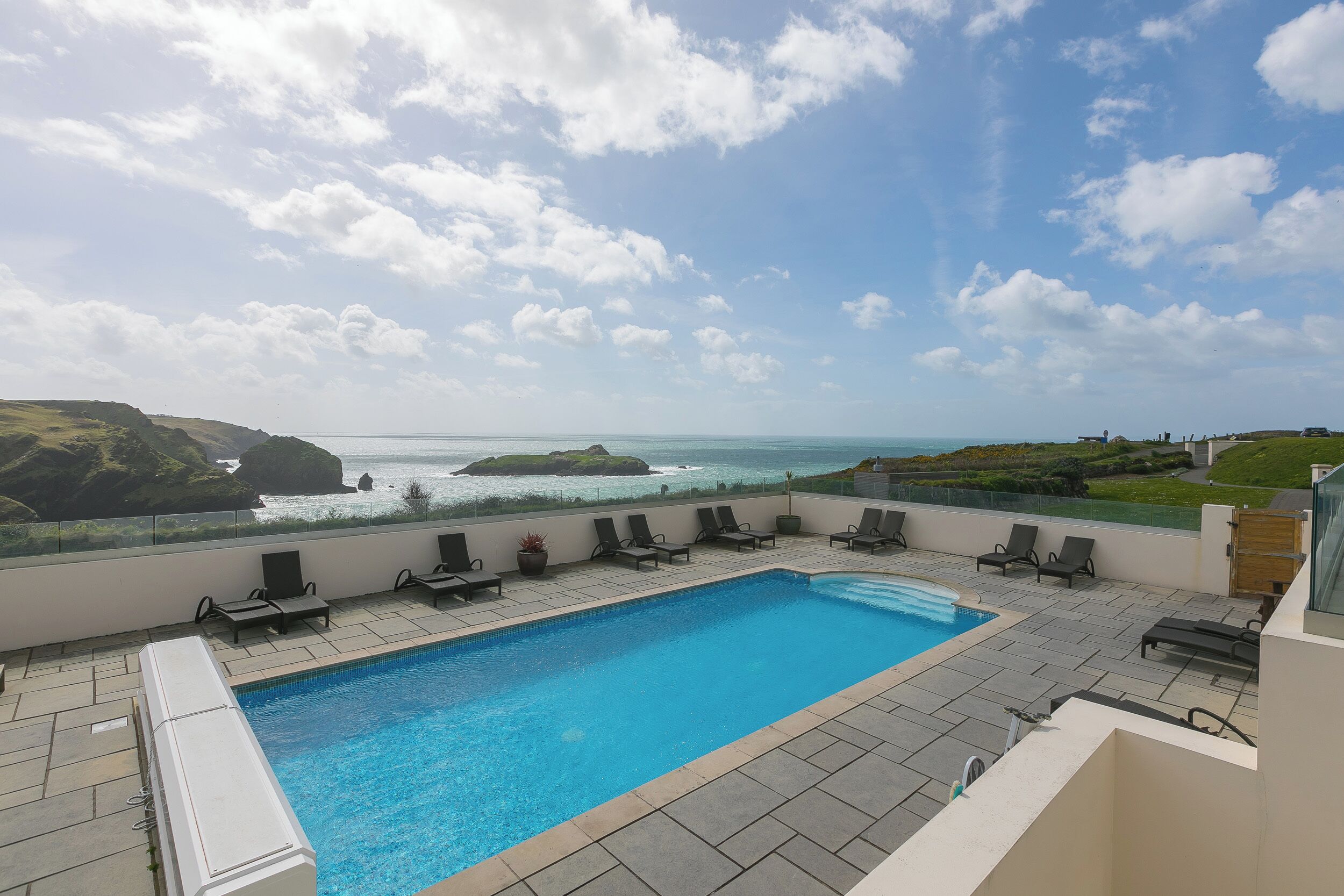 A rooftop pool with a view of the ocean and hills.