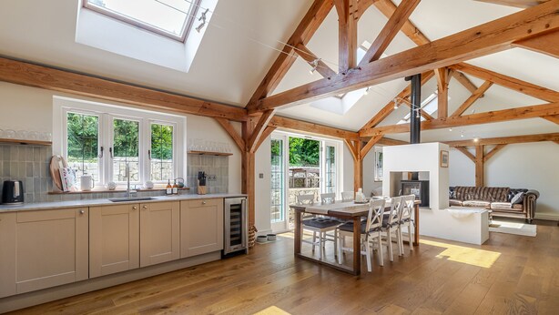 Una cocina amplia con vigas de madera, un comedor y ventanas grandes.