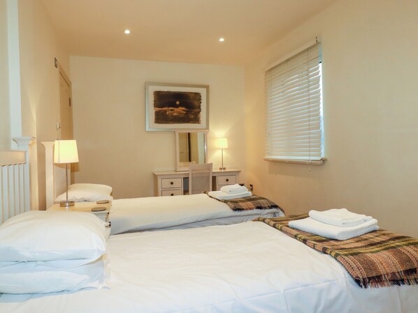 A hotel room with two beds, a dresser, a mirror, and a window with blinds. - Blue Horizon (Port Isaac)