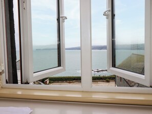 A window with a view of a calm sea and distant land. - Blue Horizon (Port Isaac)