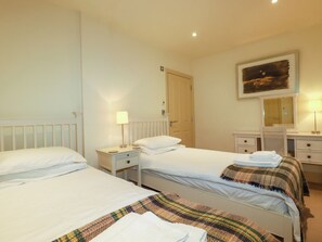 A hotel room with two single beds, a nightstand with a lamp, a dresser, and a mirror. - Blue Horizon (Port Isaac)