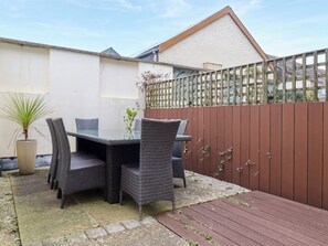 A patio with a table and chairs, a potted plant, and a wooden deck. - Blue Horizon (Port Isaac)