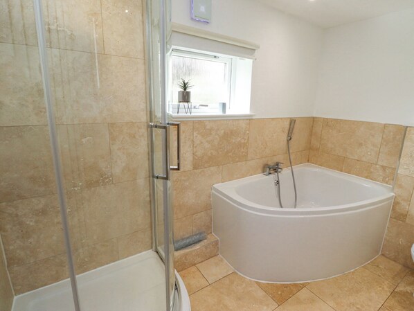 A modern bathroom with a glass-enclosed shower, a freestanding bathtub, and a window above the sink. - Waters Edge (Alnwick)