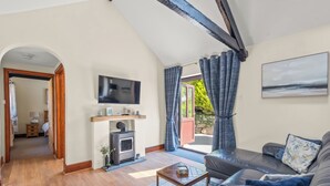 Una sala de estar con chimenea, un sofá, un televisor y vistas al exterior.