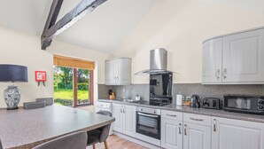 Una cocina moderna con gabinetes blancos, encimera de granito, horno integrado, microondas y estufa a gas.