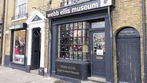Fachada de una tienda con un letrero que dice 'Webb Ellis Museum Rugby Football Museum'.