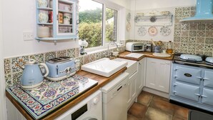 Una cocina con ventana, un armario azul, un tostador, un microondas y una estufa.