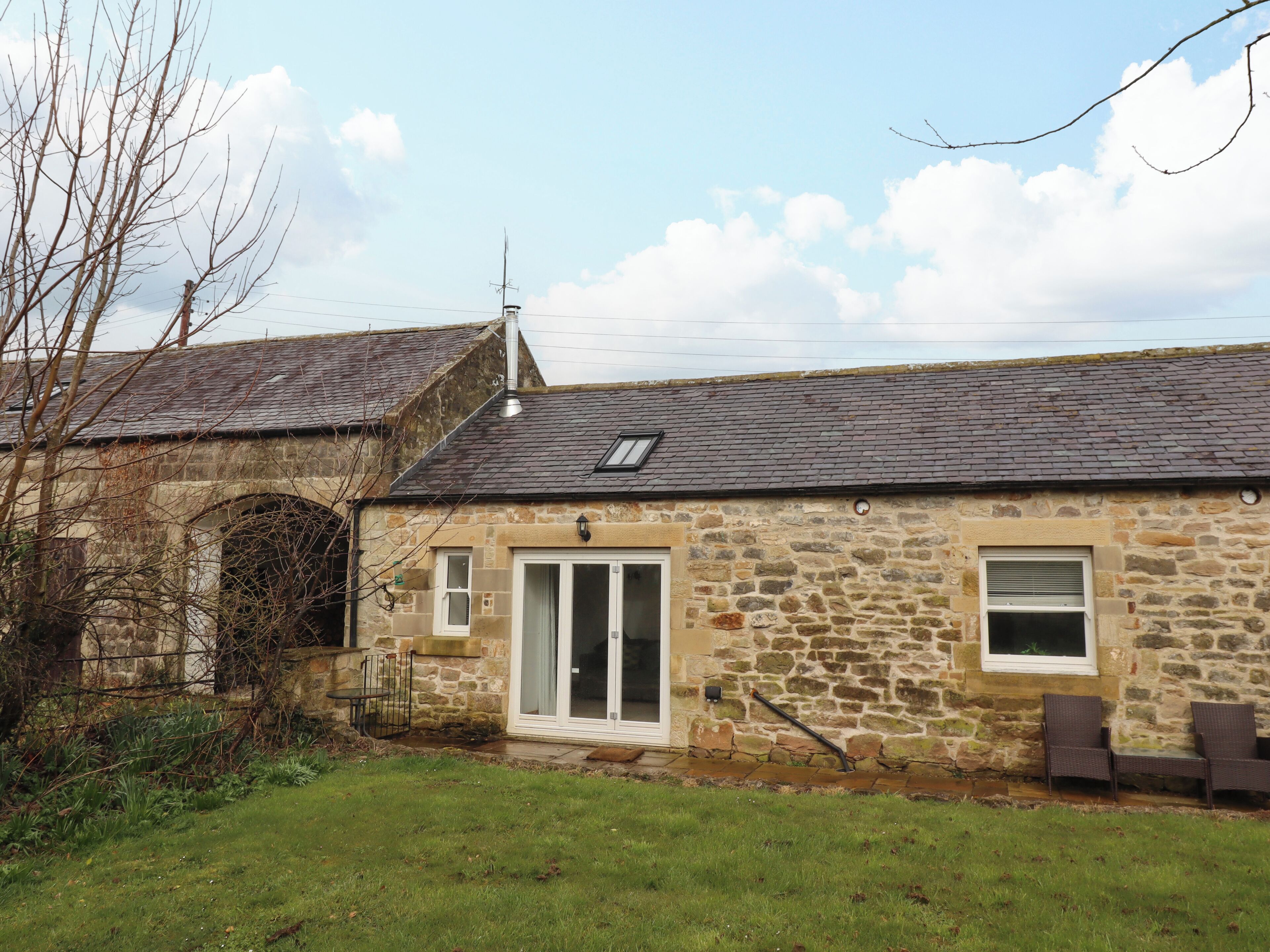 A stone house with a tiled roof, a glass door, and a small window.