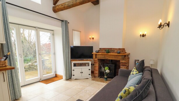 Una sala de estar con sofá, televisor, chimenea y puerta corrediza de vidrio que da a un jardín.